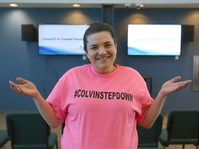 Chestermere resident Kerianne Sproule gestures and displays a message on a custom-made T-shirt as she and a handful of residents wait in the lobby in City Hall in Chestermere, east of Calgary on Friday, February 24, 2023.