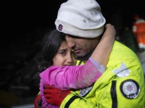 Police officer Zekeriya Yildiz hugs his daughter after they saved her from the rubble in Hatay on February 6, 2023, after a 7.8-magnitude earthquake struck the country's south-east. - A major 7.8-magnitude earthquake struck Turkey and Syria, killing more than 3,000 people and flattening thousands of buildings as rescuers dug with bare hands for survivors.