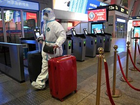 A passenger wearing personal protective equipment to halt the spread of COVID-19 arrives at a train station in Beijing, Jan. 5, 2023.