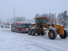 A grader helps to pull a Calgary Transit bus up Cemetery Hill on Macleod Trail following heavy overnight snow in Calgary on Feb. 21.