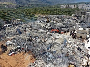 This aerial photo shows residents, assisted by heavy equipment, search for victims and survivors amid the rubble of collapsed buildings after an earthquake in the village of Besnia near the town of Harim, in Syria's rebel-held northwestern Idlib province on the border with Turkey, on February 6, 2022.