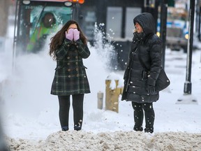 A pedestrian keeps her face warm in downtown Calgary as snow and cold temperatures sweep back into the city on Tuesday, Feb. 21, 2023.