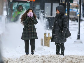 A pedestrian keeps her face warm in downtown Calgary as snow and cold temperatures sweep back into the city on Tuesday, Feb. 21, 2023.