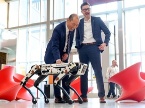 Alberta Culture Minister Jason Luan and Telus Spark Interim CEO Roderick Tate enjoy watching Flint the robot dog at the science center in Calgary on Monday, February 27, 2023.