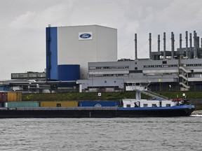 FILE - A container ship passes the Ford car plant in Cologne, Germany, May 4, 2020. Ford said that it will cut 3,800 jobs in Europe over the next three years in an effort to streamline its operations as it contends with economic headwinds and increasing competition on electric cars. The automaker said that 2,300 jobs will go in Germany.