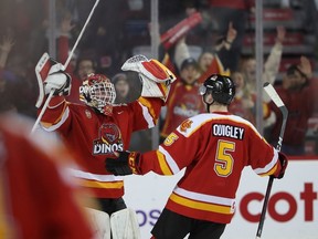Calgary goaltender Carl Tetachuk, left, and defenceman Matthew Quigley celebrate after the Dinos’ 4-2 win over the Mount Royal University Cougars at the Scotiabank Saddledome in Calgary on Jan. 17, 2023.