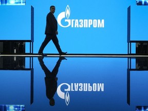 A man walks at an exhibition at the St. Petersburg International Gas Forum in St. Petersburg, Russia, Wednesday, Sept. 14, 2022, with a logo of Russian gas monopoly Gazprom in the background. Canada's trade with Russia plummeted in the first 10 months after Moscow's invasion of Ukraine a year ago, with Ottawa's economic measures barring the export of everything from forklifts to barbers' chairs.
