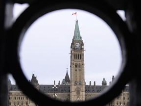 The Parliament Hill Peace Tower is framed in an iron fence on Wellington Street in Ottawa on Thursday, March 12, 2020. An annual survey on how trusting Canadians are suggests their faith in governments is rebounding as the COVID-19 pandemic begins to fade.