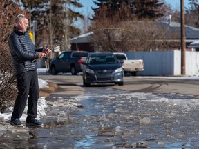 Dean Dolph jokingly tries fishing at the huge puddle formed from the melting snow outside his house in Southwest Calgary on Wednesday, March 22, 2023.