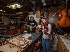 Ukrainian violinist Anastasiia Lykhorstova plays the violin gifted to her by luthier Ross Hill, standing next to her, at Hill's store in Calgary.