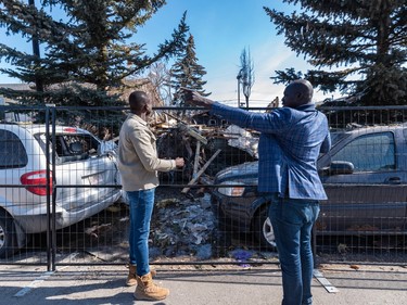 Aleer Deng, left, whose friends and relatives lived in the house that exploded after a gas leak on Tuesday morning on Maryvale Way N.E. and Gar Gar, South Sudanese community and youth advocate, take a look at the aftermath of the explosion on Thursday.
