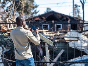 Aleer Deng, whose friends and relatives lived in the house that exploded after a gas leak on Tuesday morning on Maryvale Way N.E., takes a photo of the aftermath of the explosion.