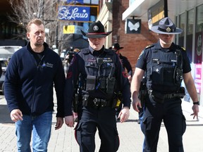 Minister of Public Safety and Emergency Services Mike Ellis (L) walks with a CPS member and an Alberta Sherriff on a tour of East Village and part of downtown Calgary on Thursday, March 23, 2023.