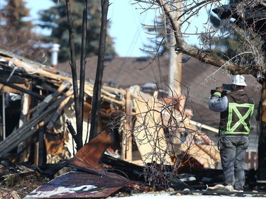 An investigator takes a photo of the carnage created by an explosion on Maryvale Way N.E. in Calgary on Monday, March 27, 2023.