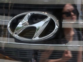 A woman's reflection is seen through the window of a Hyundai dealership in Seoul.
