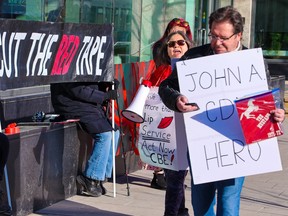 A lone counter protester walks with other protesters who gathered outside the Calgary Board of Education building to call for an end to delays in changing the name of John A. Macdonald Junior High School and the mascot name for John G. Diefenbaker High School.