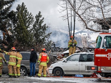 Firefighters attend the scene of a house explosion that injured several people, destroyed one home and damaged others in Calgary, Alta., Monday, March 27, 2023.