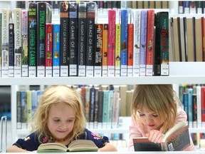 Sisters Sophie and Olivia dive into some books during the opening of the Central Library in Calgary in 2018. Jim Wells/Postmedia