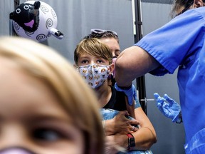FILE - Finn Washburn, 9, receives an injection of the Pfizer-BioNTech COVID-19 vaccine in San Jose, Calif., on Nov. 3, 2021, as his sister, Piper Washburn, 6, waits her turn. California's COVID-19 emergency declaration ends on Tuesday, Feb. 28, 2023. Public health experts say the pandemic has not ended, but the virus is much more manageable with the availability of vaccines and other treatments.