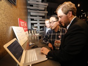 Peter McCaffrey of No Calgary shows Councilor Sean Chu incoming votes for the 2026 Olympics plebiscite at the Kensington Legion in Calgary on Tuesday, November 13, 2018.