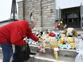 Church volunteer Daniel Theriault places a plush toy on the steps of the church, Tuesday, March 14, 2023 in Amqui, Que. Two people were killed and nine others were injured Monday afternoon when a pickup truck plowed into pedestrians who were walking beside a road in the eastern Quebec town of Amqui.