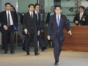 Japanese Prime Minister Fumio Kishida, front, arrives without wearing a face mask at his office in Tokyo on Monday, March 13, 2023. Japan on Monday dropped its request for people to wear masks after three years, but hardly anything changed in the country that has had an extremely high regard for their effectiveness at anti-virus protection. Kishida, as well as his body guards, wasn't wearing a mask when he arrived at his office Monday.