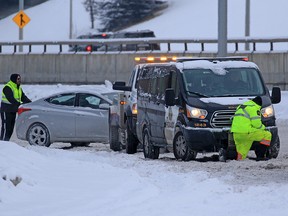 Tow truck drivers come to the aid of vehicles, including a police van, stuck on a slippery stretch of Bow Trail S.W. on Feb. 3, 2021.