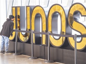 A passer-by catches his reflection in one of two large JUNOS award signs that have appeared around Rogers Place in Edmonton for the awards ceremony on March 13. on March 7, 2023.     Photo by Shaughn Butts-Postmedia
