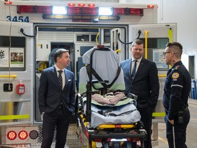 Matt Stevenson, operations supervisor of Calgary Zone with Alberta Health Services, demonstrates the features of a stretcher used in the EMS ambulances to Alberta Health Minister Jason Copping, left, and RJ Sigurdson, parliamentary secretary for EMS reform, after at a press conference announcing additional supports to lower EMS response times at the StoneGate EMS station in Calgary on April 3.