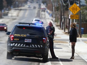 A Calgary police officer talks with a sex worker on 19th Avenue and 48th Street S.E. in Calgary on Tuesday, April 11, 2023. She said she has eight kids, can make up to $1,500 per day or nothing, and fears not only the violence and crime but often fears for her life.