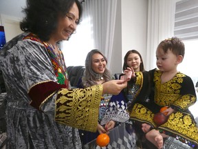 One year old  Alisa Abdulzada receives Eidy (a gift) from Gulshan Mahmoodi as mom Qadria Mahmody (second from left) and teen Rubena Abdulzada looks on as family members celebrate Eid at a home in Chestermere, east of Calgary on Friday, April 21, 2023. Family includes Mom Qadria Mahmody, son Sahil Abdulzada, daughter Rubena Abdulzada and grandmother Gulshan Mahmoodi and grandfather Qadir Mahmoodi.