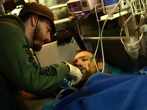 A paramedic volunteer with Hospitallers treats a Ukrainian serviceman on a medical bus bound for a hospital in Dnipro on April 11.  The soldier was injured during Russia's attack on Bakhmut.