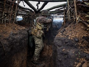 A Ukrainian infantryman fires an assault rifle at enemy positions from a trench near the town of Bakhmut on April 13.