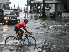 FILE: A cyclist rides through the flooded street during heavy rain and wind as tropical storm Eta approaches the south of Florida, in Miami, Florida on November 9, 2020.