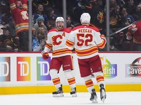 Calgary Flames forward Jonathan Huberdeau, back, celebrates his game-tying, third-period goal against the Vancouver Canucks with MacKenzie Weegar at Rogers Arena in Vancouver on Friday, March 31, 2023.