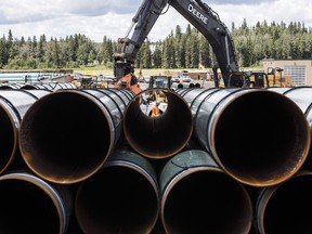 Pipes for the Trans Mountain pipeline are unloaded in Edson, Alta.