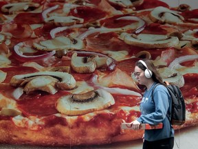 A pedestrian walks past a mural advertising pizza in Toronto. Pizza Pizza, Canada's biggest pizza chain, is expanding to Mexico.