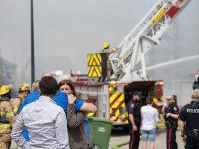A resident of one of the three houses fully involved in a fire on Cougartown Close S.W. find some comfort in hugging her acquaintances on Wednesday, May 3, 2023.