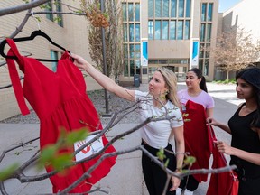 Nursing student Emilie Ferguson along with her fellow nursing students at Mount Royal University hang red dresses around the campus prior to the national day of awareness for Missing and Murdered Indigenous Women (MMIW) on Thursday, May 4.