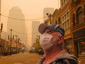 Barry Larence wore a mask as extra protection from thick forest fire smoke that created an  
eerie glow in downtown Calgary on Tuesday, May 16, 2023. 
Gavin Young/Postmedia