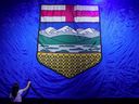 A worker irons a giant Alberta flag as he sets the stage for the United Conservative Party's provincial election night party in Calgary on May 29, 2023.