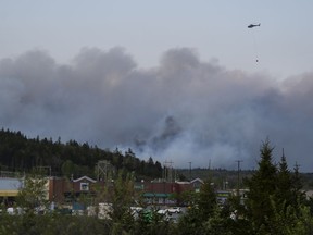 A helicopter carrying water flies over heavy smoke from an out-of-control fire in a suburban community outside of Halifax that spread quickly, engulfing multiple homes and forcing the evacuation of local residents on Sunday May 28, 2023.THE CANADIAN PRESS/Darren Calabrese
