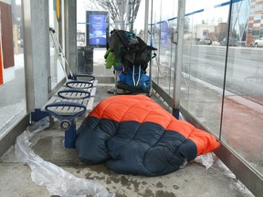 A man lays in a bus shelter near 12th Street and 16th Avenue N.W.