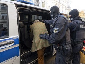 FILE - Masked police officers lead an arrested suspect, left, to a police vehicle during a raid against so-called 'Reich citizens' in Frankfurt, Germany, Wednesday, Dec. 7, 2022. The number of politically motivated crimes reported in Germany rose by 7% last year, Germany's top security official said Tuesday, May 9, 2023.