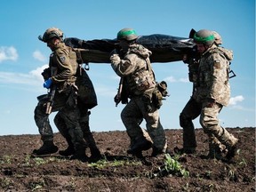 Members of Ukraine's International Legion carry the body of Calgary volunteer Kyle Porter after recovering it from where he was killed along with Canadian Cole Zelenco by Russian artillery shells on April 26 at Bakhmut, Ukraine.