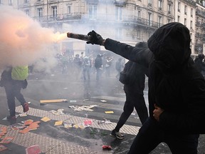 A protester shoots a firework during a demonstration on May Day, to mark the international day of the workers, more than a month after the government pushed an unpopular pensions reform act through parliament, in Paris, on May 1, 2023.