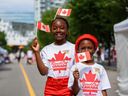 Makalah, 9, and her brother Sawlah, 7, pose for a photo after getting their temporary maple leaf face tattoos at the East Village street fair during Canada Day celebrations on Friday, July 1, 2022.