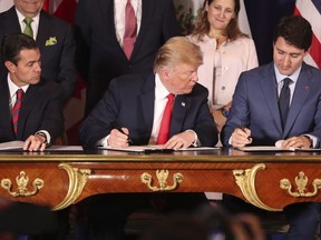 President Donald Trump, centre, looks over at Prime Minister Justin Trudeau's document as they and Mexico's President Enrique Pena Nieto sign the new United States-Mexico-Canada Agreement in Buenos Aires, Argentina, Friday, Nov. 30, 2018.