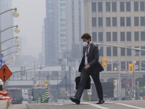 A man walks to work wearing a mask near Parliament Hill, Wednesday, June 7, 2023 in Ottawa. The battle against hundreds of wildfires continued Thursday, as almost every jurisdiction in Canada was under either heat or air quality warnings from the federal government.