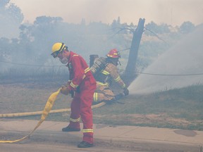 Calgary firefighters deal with a large grass fire on McHugh Bluff below Crescent Heights that burned into the backyards of homes along the ridge on Monday, June 5, 2023.